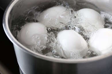 Photo of Chicken eggs boiling in saucepan, closeup view
