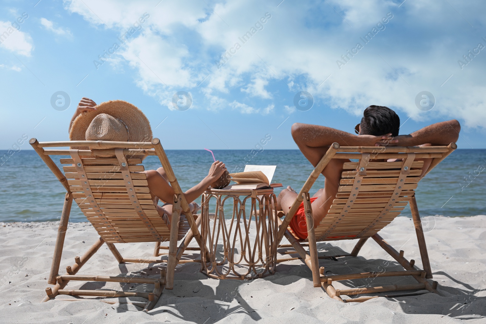 Photo of Couple resting in wooden sunbeds on tropical beach