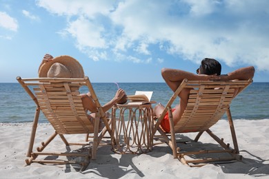 Photo of Couple resting in wooden sunbeds on tropical beach