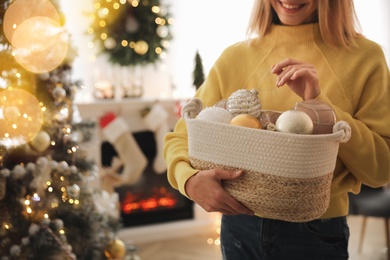 Woman decorating Christmas tree at home, closeup