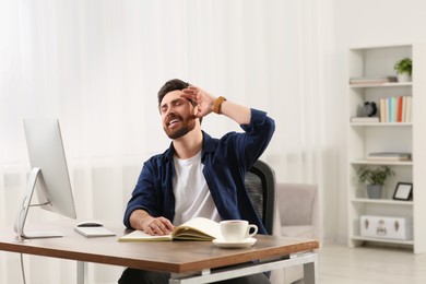 Home workplace. Emotional man working with computer at wooden desk in room