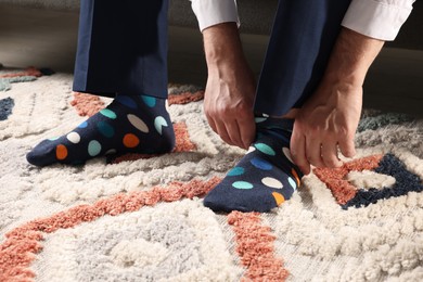 Man putting on colorful socks indoors, closeup