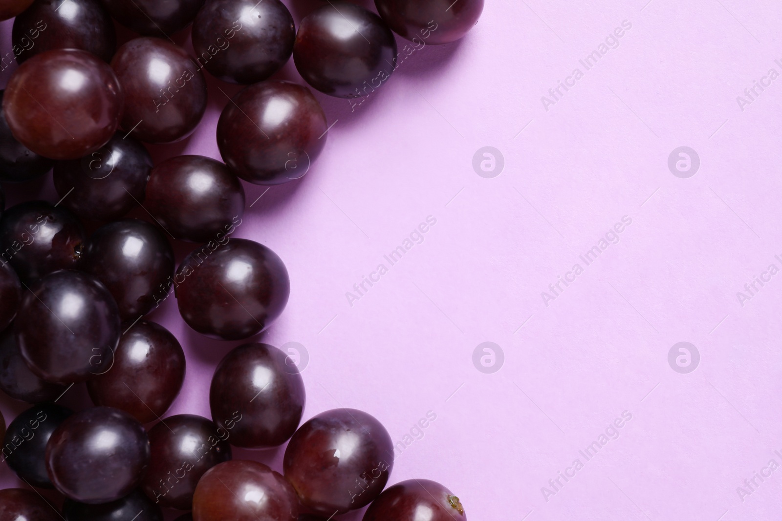 Photo of Fresh ripe juicy grapes on pink background, flat lay. Space for text