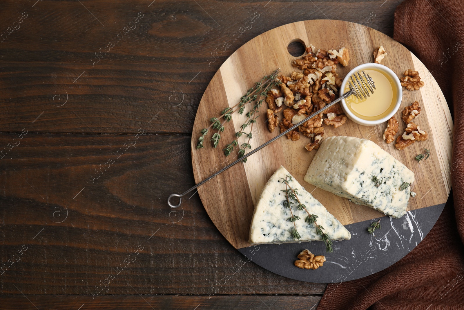Photo of Tasty blue cheese with thyme, honey and walnuts on wooden table, top view. Space for text
