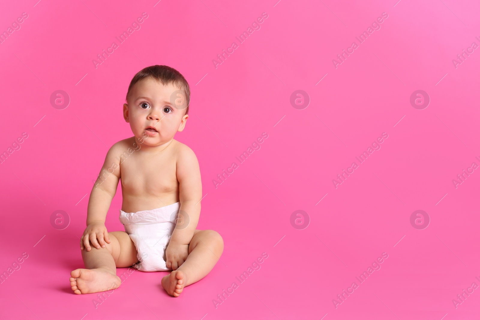 Photo of Cute baby in dry soft diaper sitting on pink background. Space for text