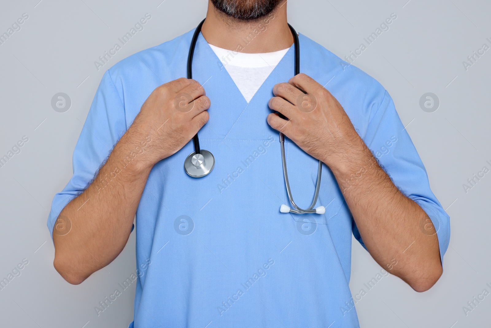 Photo of Doctor with stethoscope on light grey background, closeup
