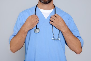 Doctor with stethoscope on light grey background, closeup