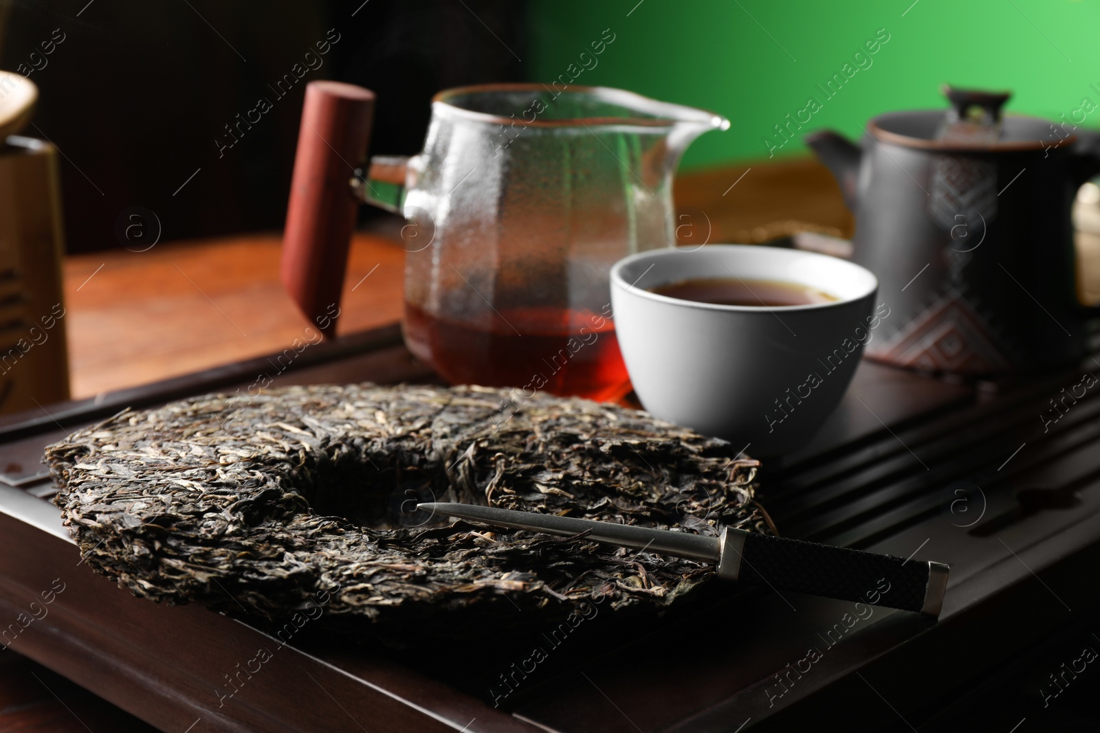 Photo of Disc shaped pu-erh tea and knife on wooden tray