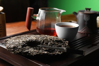 Photo of Disc shaped pu-erh tea and knife on wooden tray