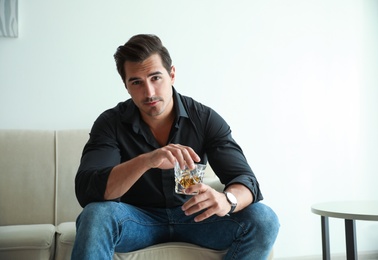 Young man with glass of whiskey at home