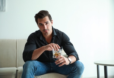 Photo of Young man with glass of whiskey at home