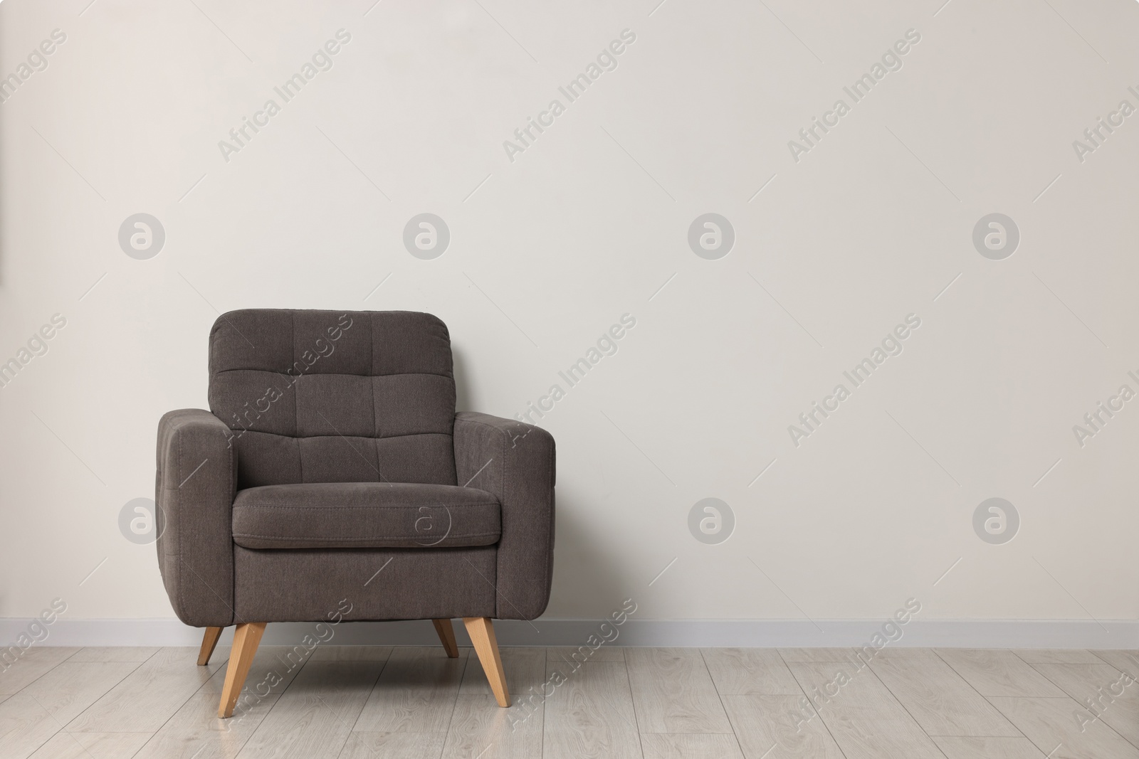 Photo of Comfortable armchair near white wall in room, space for text