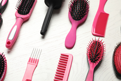 Different combs and brushes on white wooden background, closeup