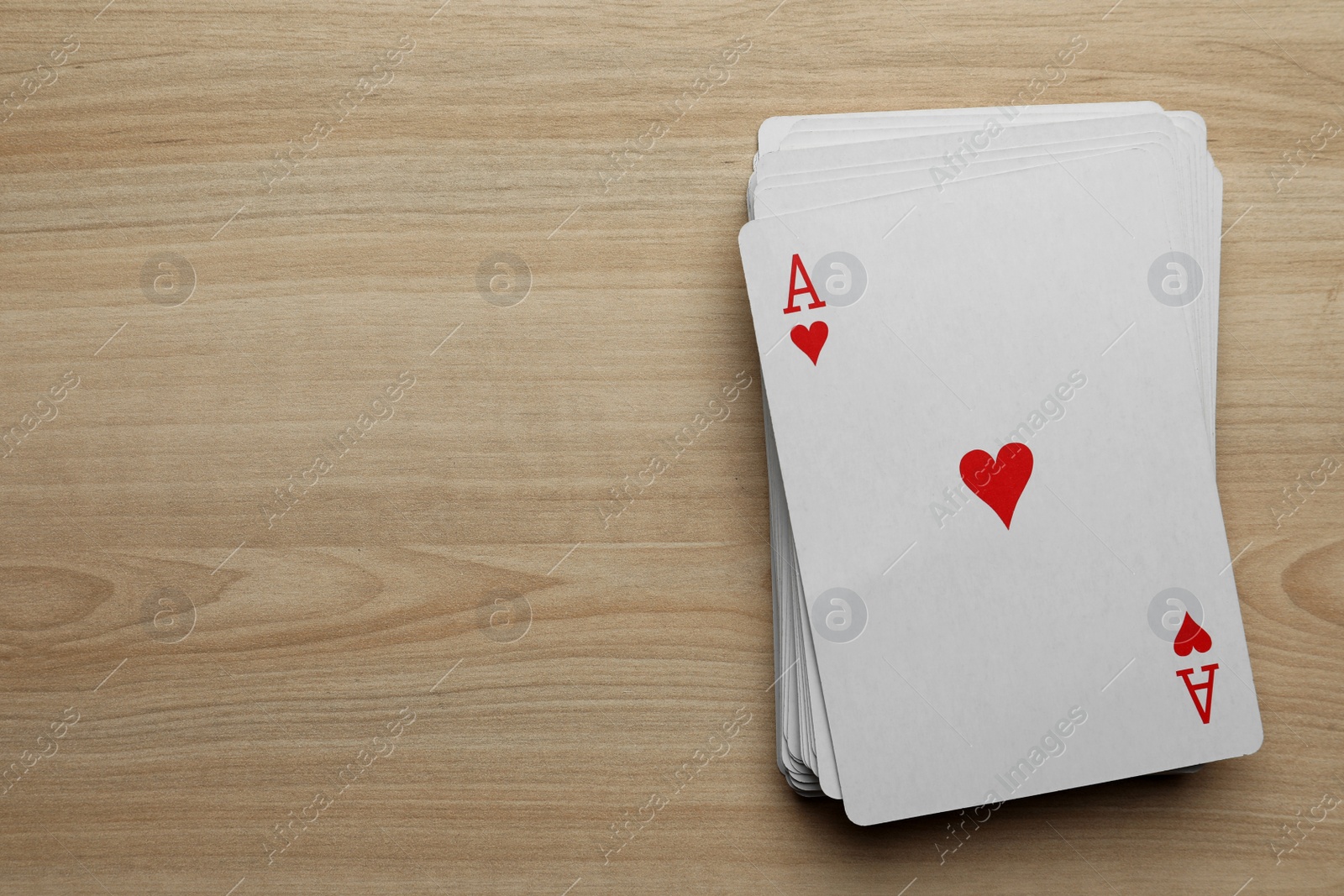 Photo of Deck of playing cards on wooden table, flat lay. Space for text