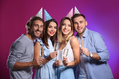 Photo of Portrait of happy friends with champagne in glasses on color background