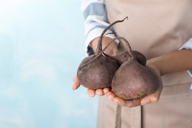 Woman holding ripe beets on light background