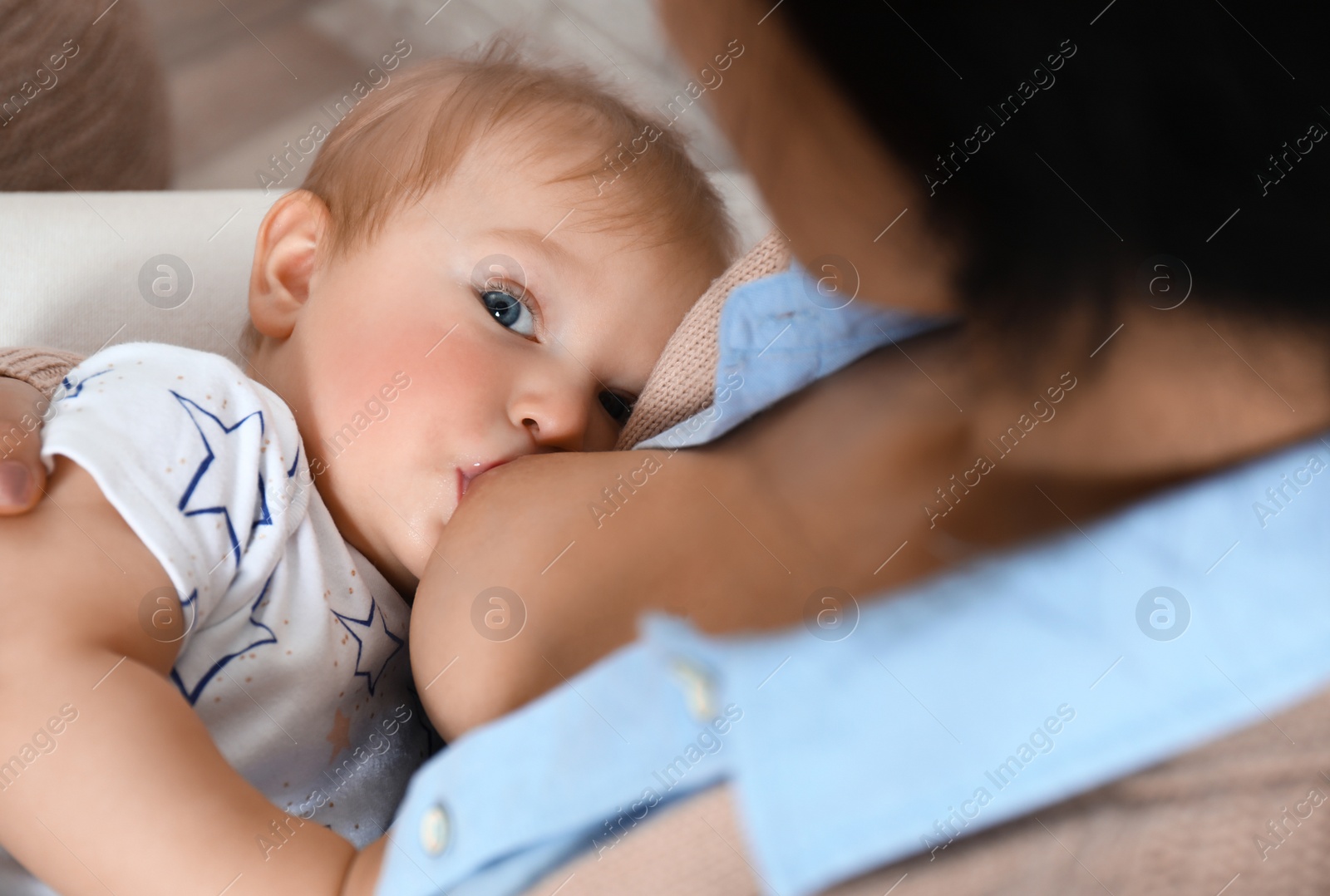 Photo of Woman breast feeding her little baby indoors, closeup