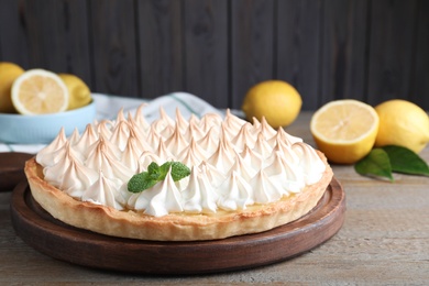 Photo of Delicious lemon meringue pie decorated with mint on wooden table