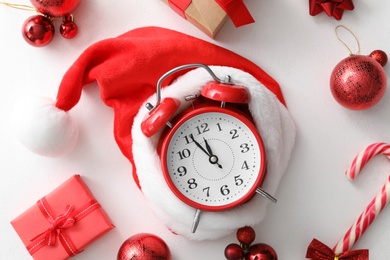 Flat lay composition with alarm clock and Christmas decor on white background. New Year countdown