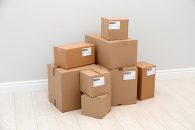 Photo of Stacked parcel boxes on floor against light wall