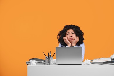 Stressful deadline. Exhausted woman sitting at white desk against orange background. Space for text