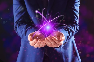 Man holding virtual model of atom on color background, closeup