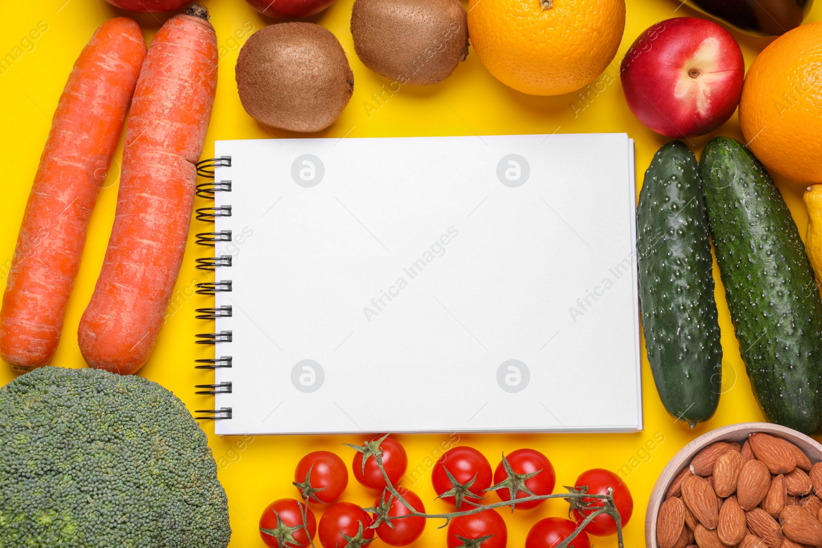 Photo of Notebook, fresh fruits and vegetables on yellow background, flat lay. Low glycemic index diet