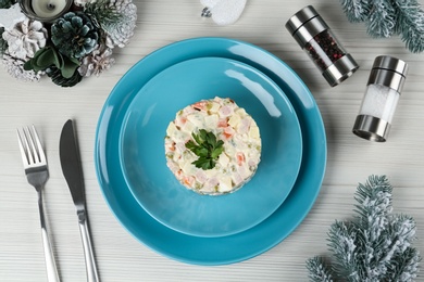 Flat lay composition with traditional russian salad Olivier on white wooden table