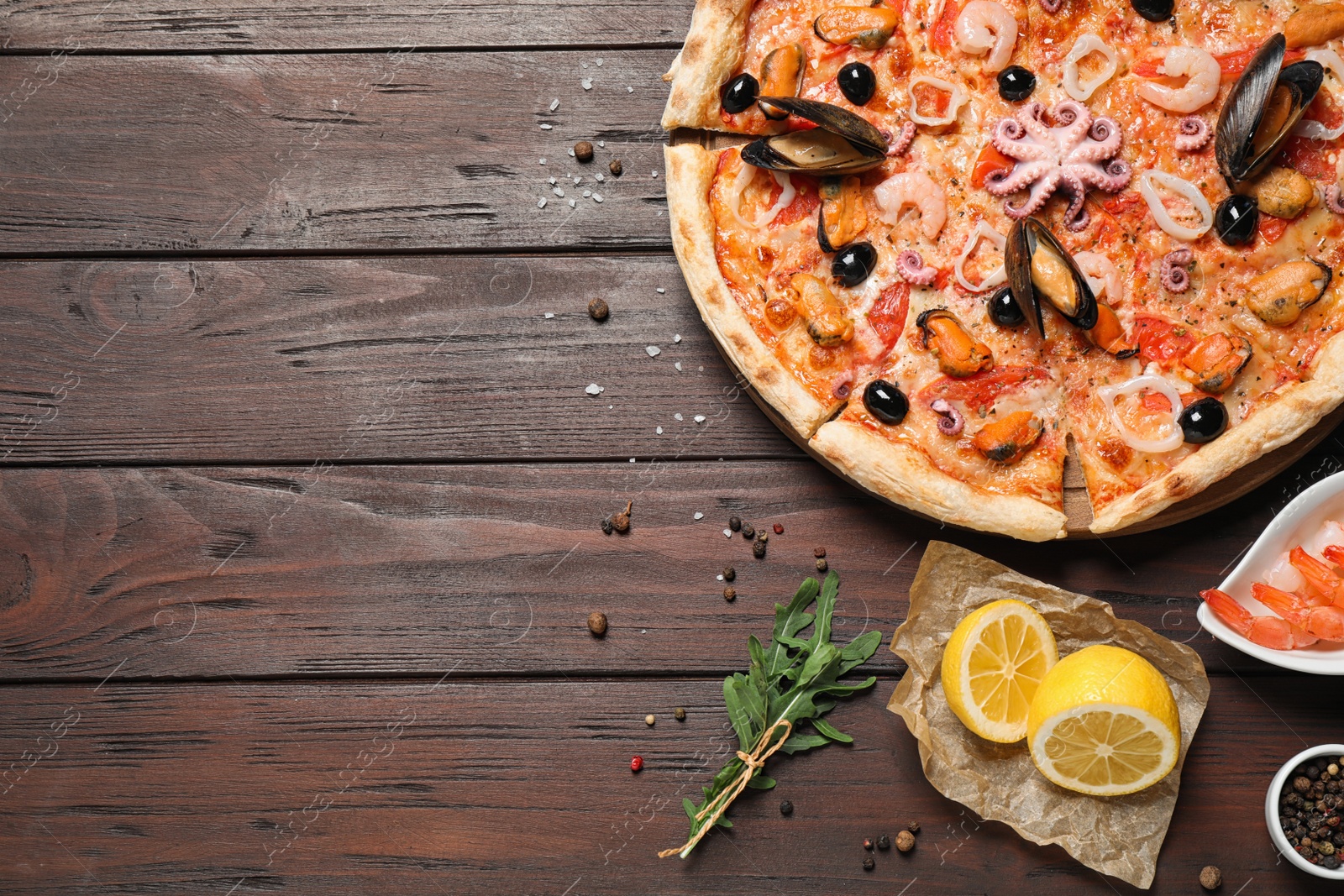 Photo of Tasty pizza with seafood and ingredients on wooden table, flat lay. Space for text