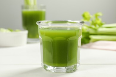 Photo of Glass of fresh celery juice on white table, closeup