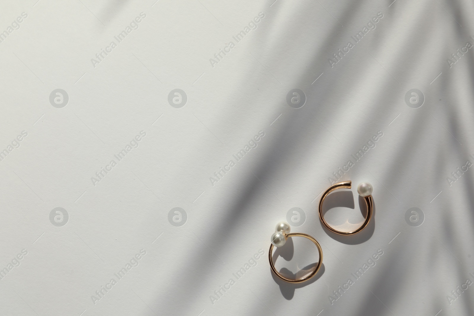 Photo of Elegant golden rings with pearls on white table, flat lay. Space for text