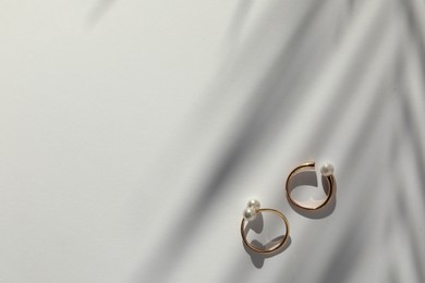 Photo of Elegant golden rings with pearls on white table, flat lay. Space for text