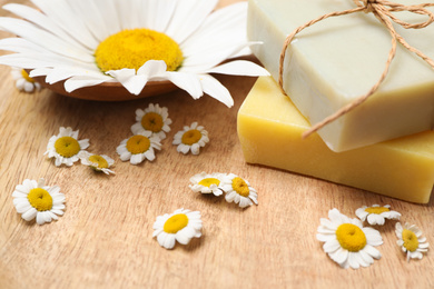 Photo of Composition with chamomile flowers and soap bars on wooden table, closeup