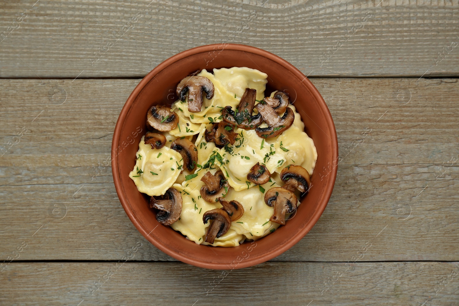 Photo of Delicious ravioli with mushrooms on wooden table, top view