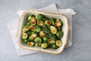 Photo of Delicious roasted Brussels sprouts and rosemary in baking dish on grey table, top view