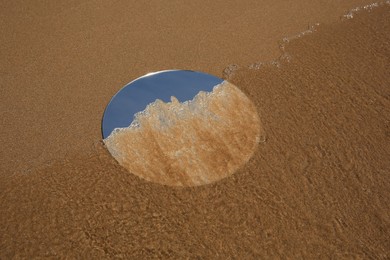 Round mirror with sand on beach outdoors