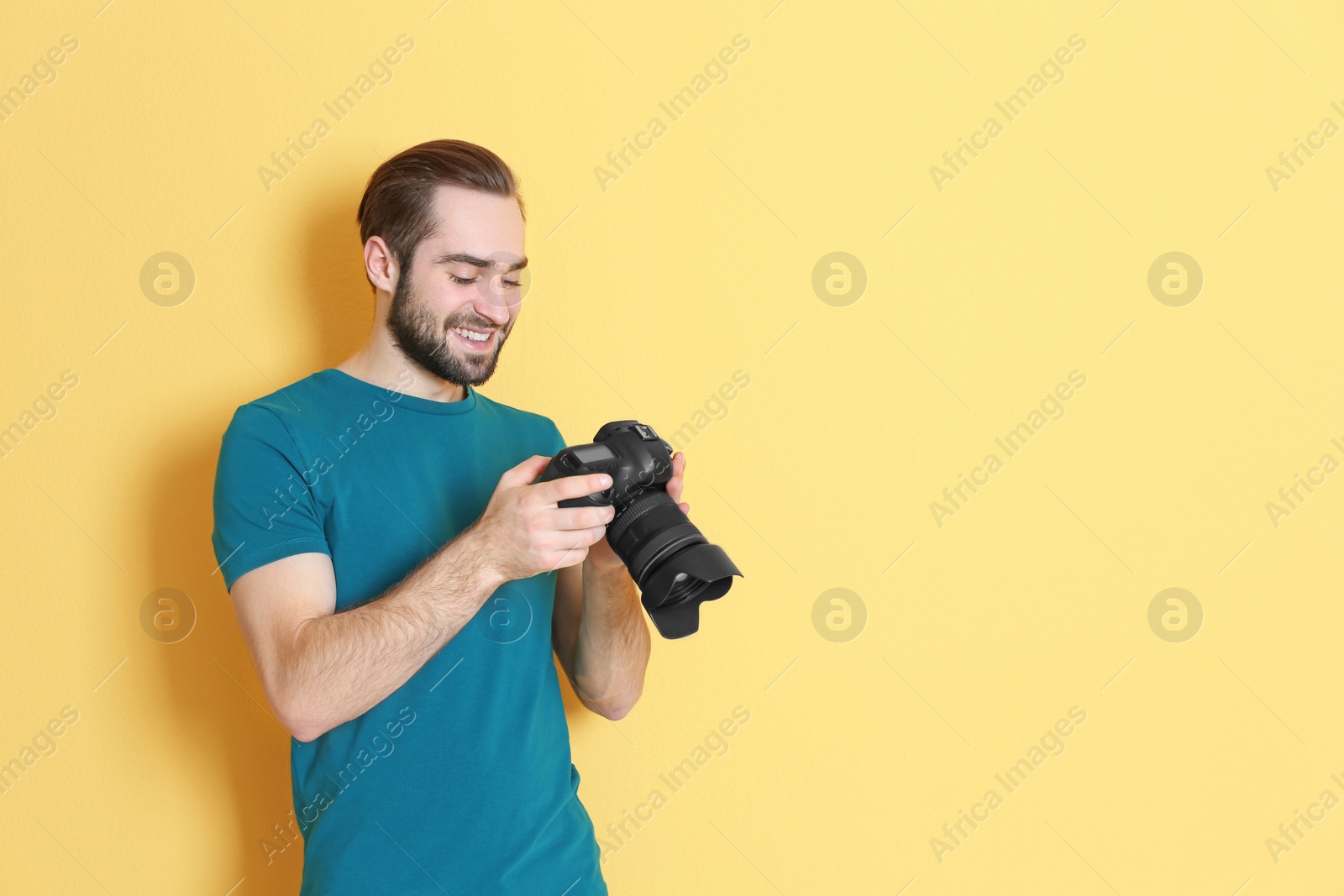 Photo of Young photographer with professional camera on color background