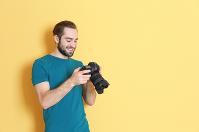 Photo of Young photographer with professional camera on color background