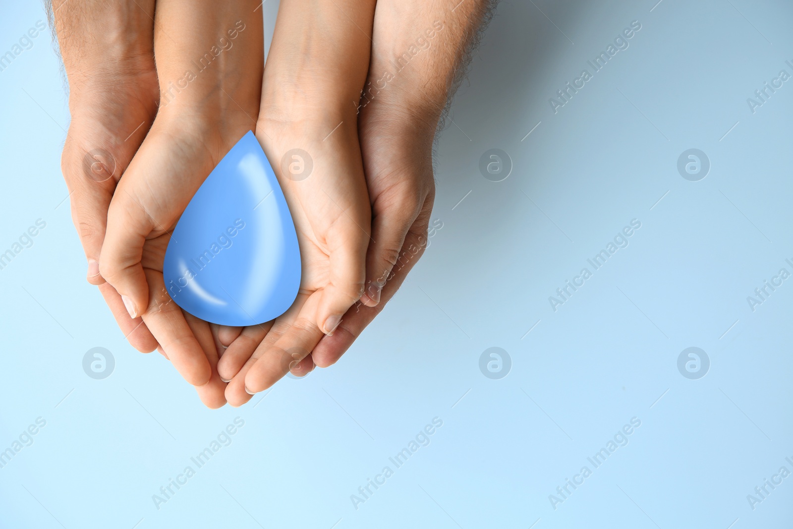 Image of Young couple holding water drop on light background, top view with space for text. Ecology protection