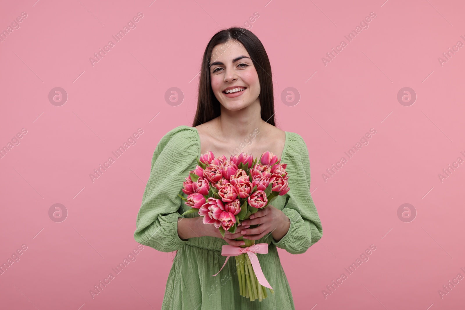 Photo of Happy young woman with beautiful bouquet on dusty pink background