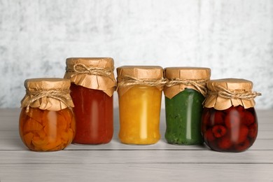 Photo of Jars with canned fruit jams on wooden table