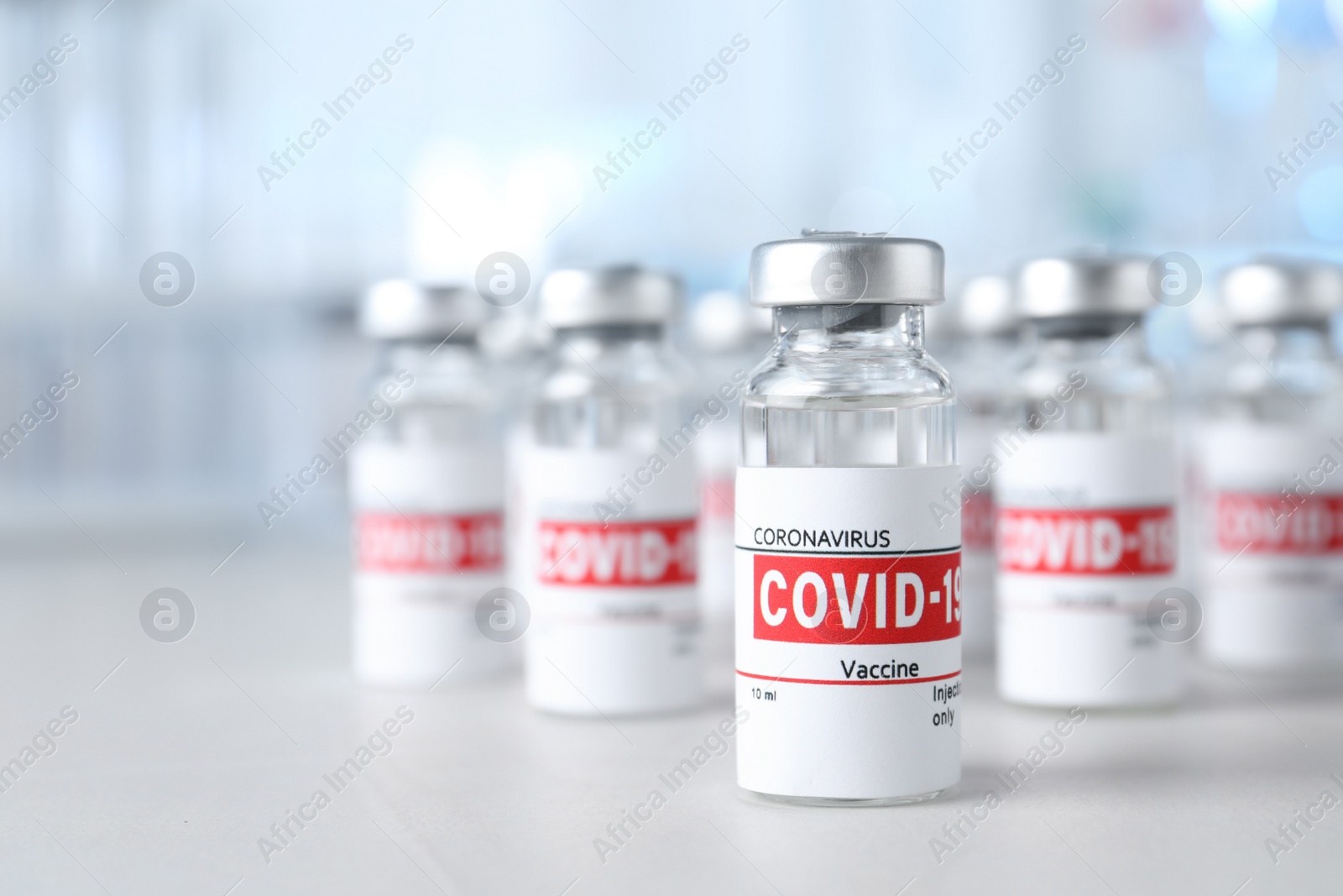 Photo of Glass vials with COVID-19 vaccine on light table. Space for text