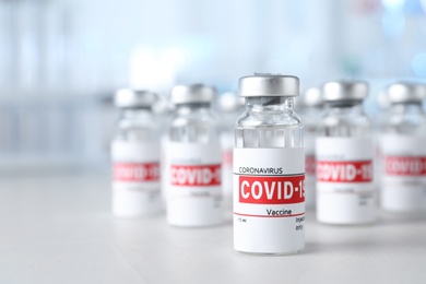 Photo of Glass vials with COVID-19 vaccine on light table. Space for text