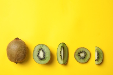 Photo of Top view of fresh cut and whole kiwis on yellow background