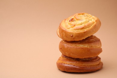 Photo of Stack of delicious rolls with raisins on beige background, space for text. Sweet buns