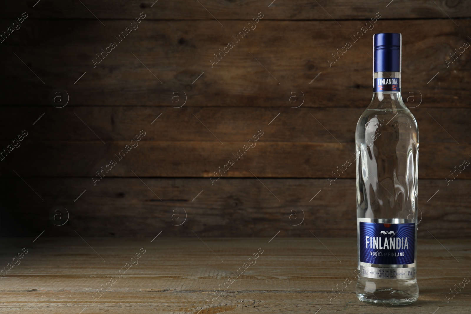 Photo of MYKOLAIV, UKRAINE - OCTOBER 03, 2019: Bottle of Finlandia vodka on table against wooden background. Space for text