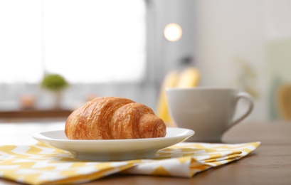 Photo of Plate with tasty freshly baked croissant on table