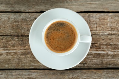 Photo of Cup of tasty coffee on wooden table, top view