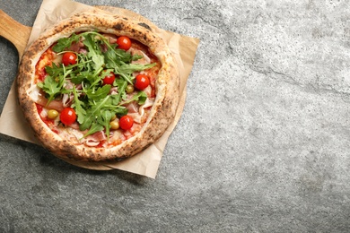 Photo of Tasty pizza with meat and arugula on grey table, top view. Space for text
