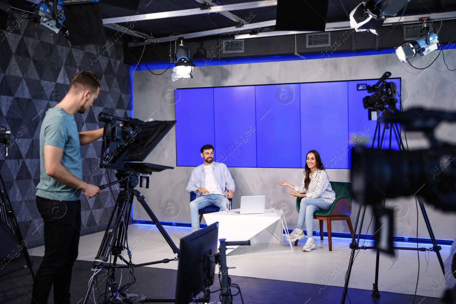 Photo of Presenters and video camera operator working in studio. News broadcasting